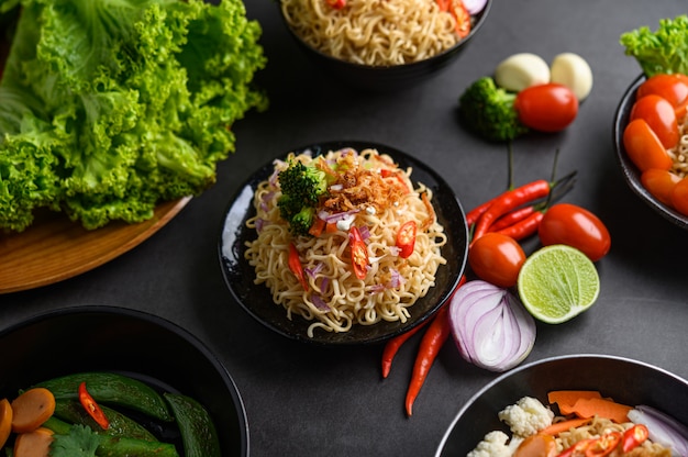 Free Photo noodles spicy in the bowl with ingredients on black cement surface