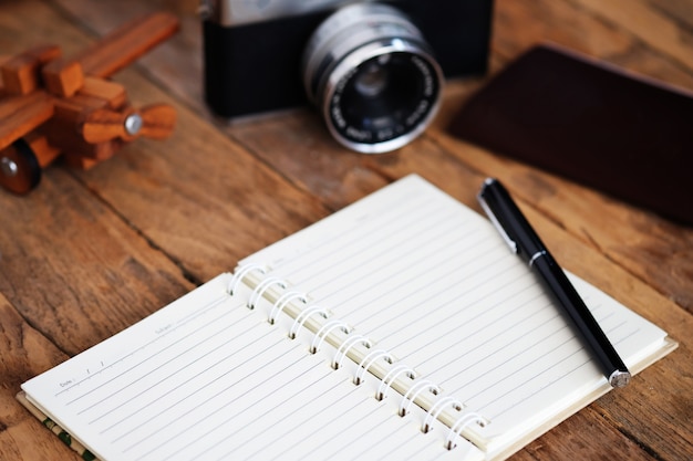 Free photo note book and travel vacation items on wooden table.