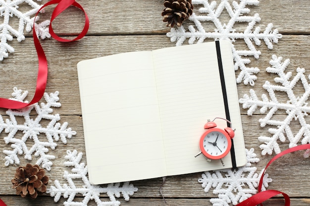 Notebook and alarm clock on snowflakes