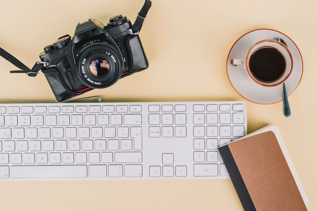 Notebook and coffee near camera and keyboard