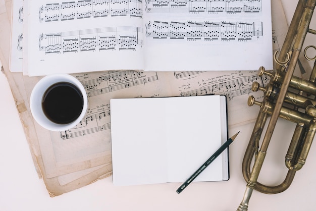 Free photo notebook and coffee near sheet music and trumpet