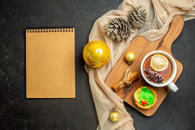 Notebook and a cup of black tea with lemon and cinnamon limes new year decoration accessories on wooden cutting board