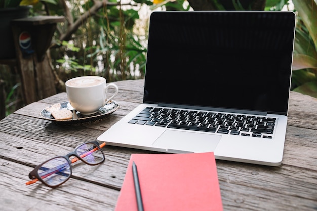 Free photo notebook and glasses near laptop and cup