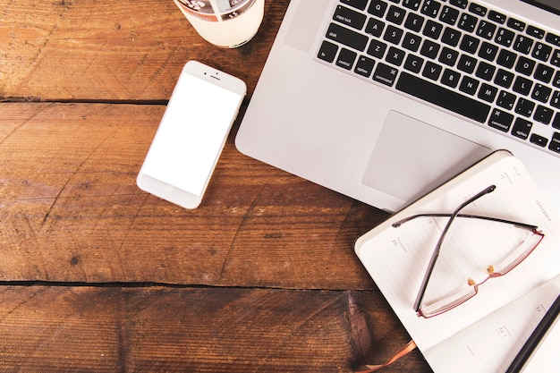 Notebook and glasses near laptop and smartphone