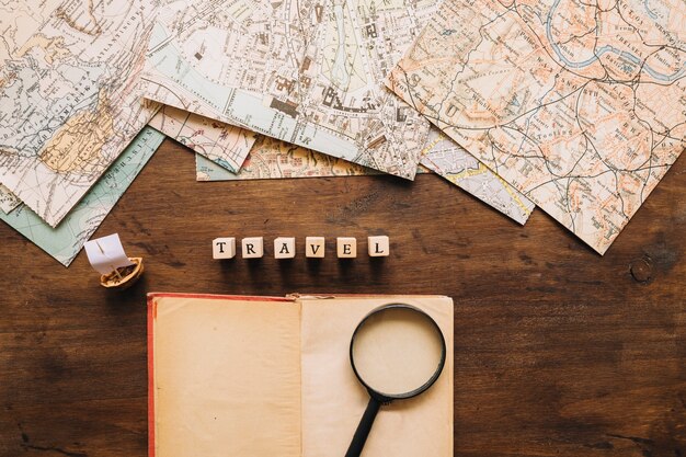 Notebook and magnifying glass near writing and maps