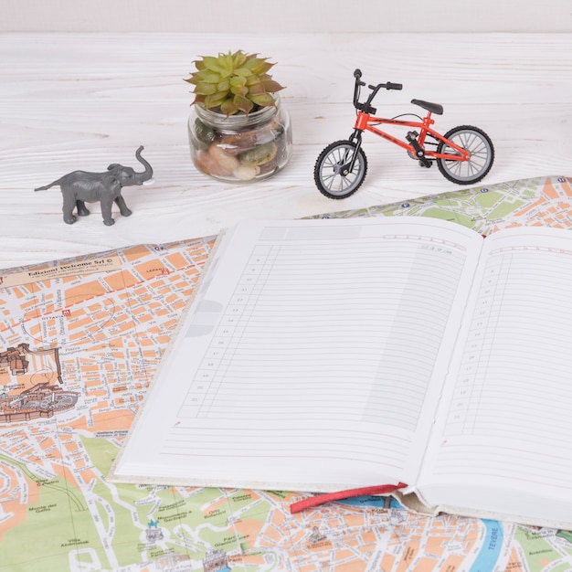 Free photo notebook on map near toy animal and bicycle