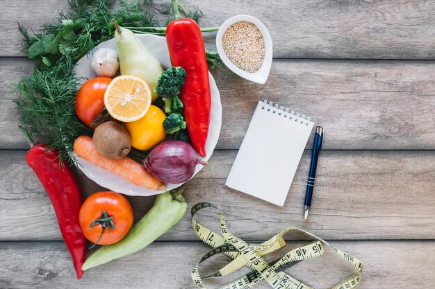 Free Photo notebook and measuring tape near vegetables and fruits