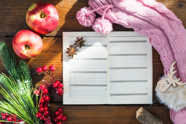 Notebook near knitted sock, twigs and apples