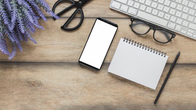 Notebook and smartphone near lavender flowers and keyboard