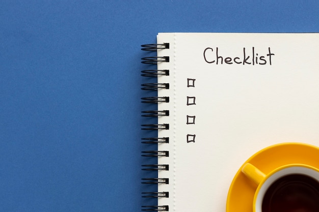 Notebook with to do list on desk with cup of coffee beside