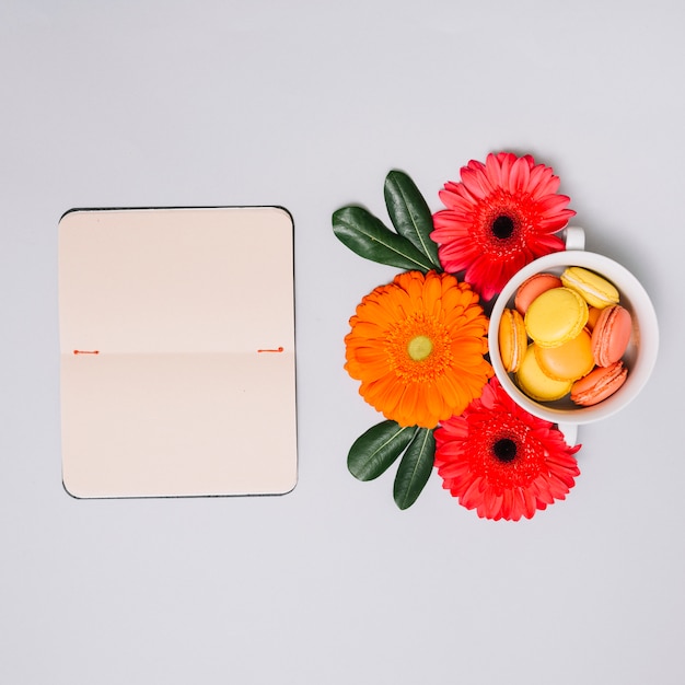 Notebook with small cookies and flowers on table