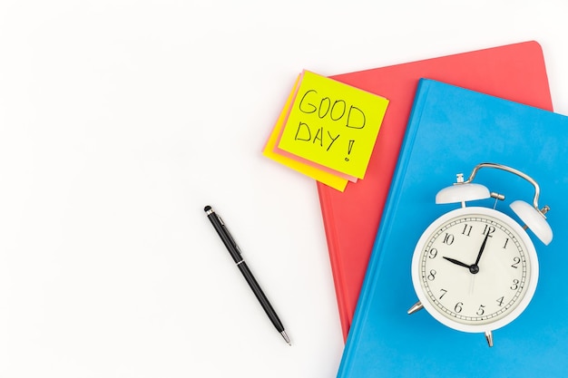 Free photo notebooks an alarm clock and a paper reminders on a white background isolated