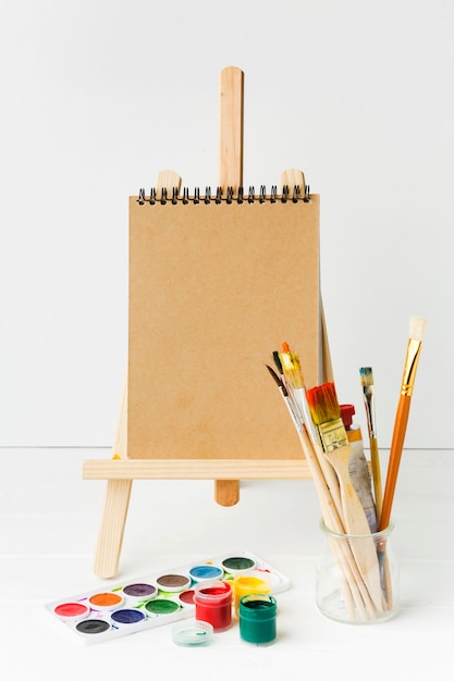 Free photo notepad on easel and paint brushes