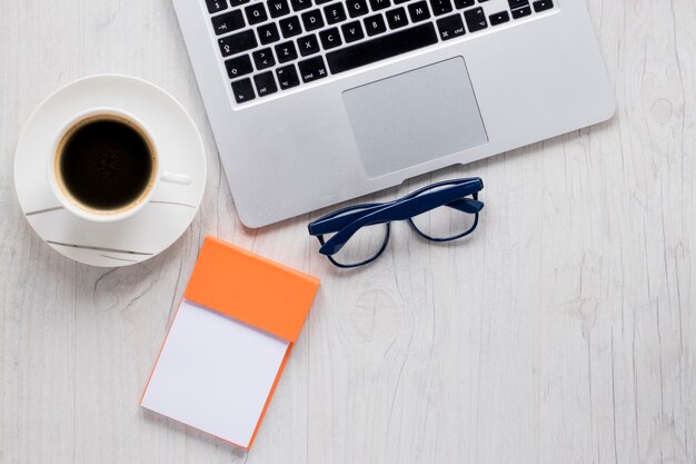 Notepad and glasses near laptop and coffee 