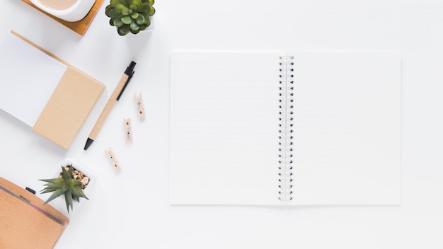 Notepad near stationery and flower pots on white table