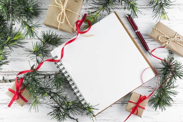 Notepad with fir tree branches on wooden table