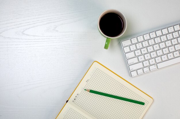 Notepad with pencil keyboard and cup of coffee