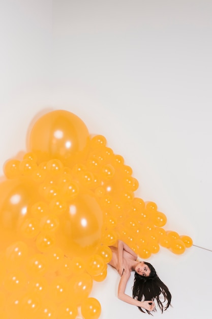 Free photo nude woman between many yellow balloons