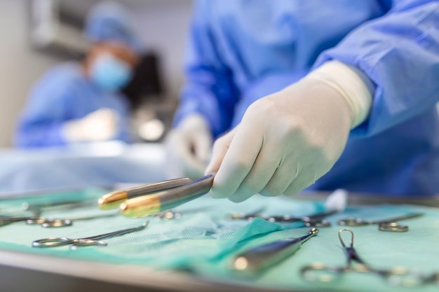 Free photo nurse hand taking surgical instrument for group of surgeons at background operating patient in surgical theatre steel medical instruments ready to be used surgery and emergency concept