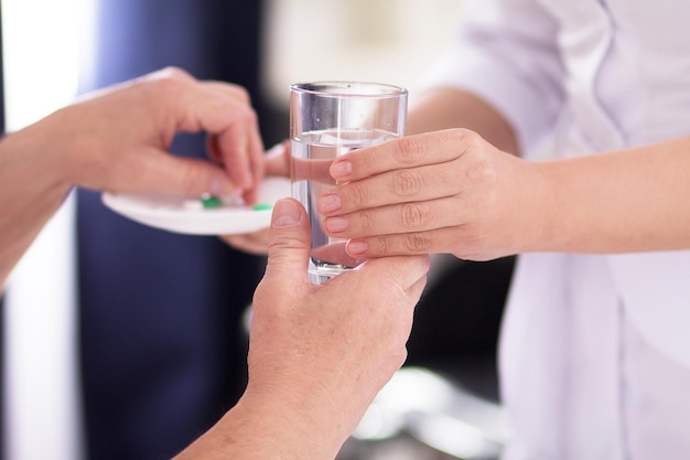 Nurse handing her patient some water