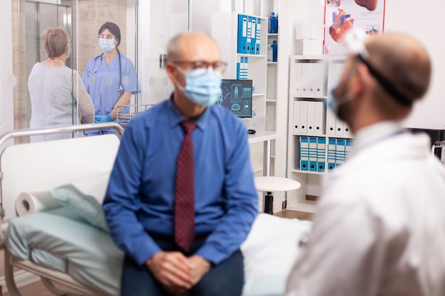 Free photo nurse in hospital corridor discussing with handicapped senior woman with walking frame