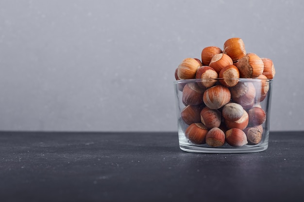 Nut shells in a glass cup on grey background on the right side. 