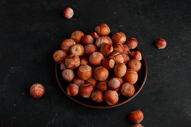 Nuts in saucer on black surface. 