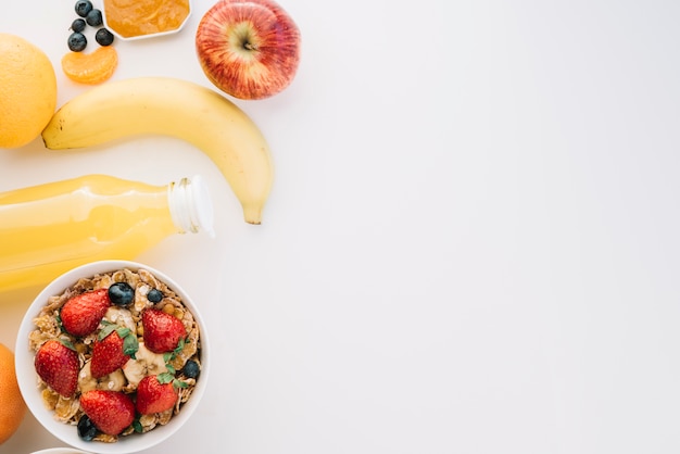 Oatmeal in bowl with different berries on white table