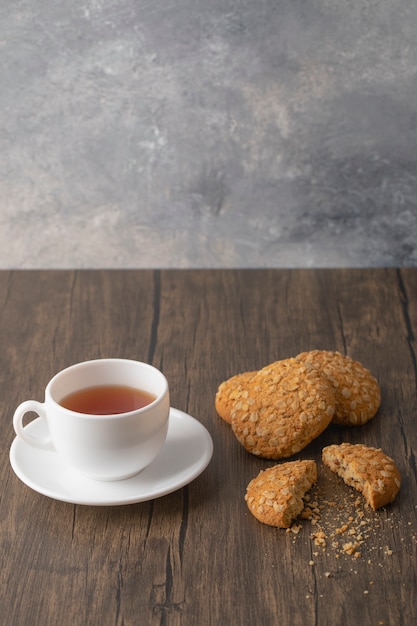 Free photo oatmeal cookies with seeds and cereals near a white cup of black tea