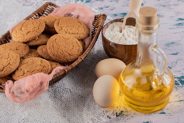 Oatmeal cookies in a wooden basket tray with ingredients around.