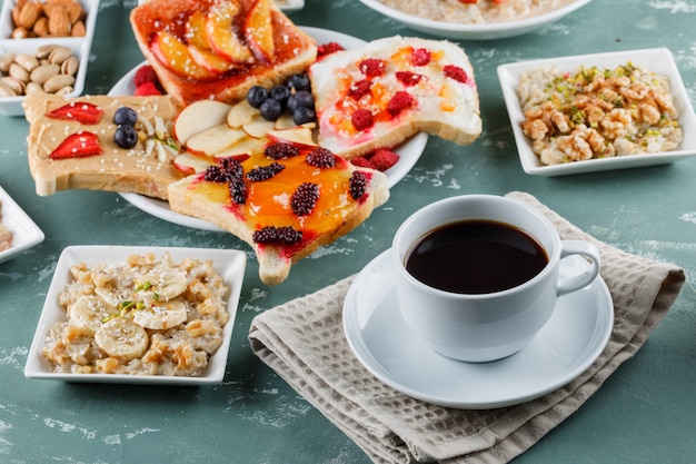 Oatmeal in plates with fruits, jam, nuts, fruit sandwich, coffee