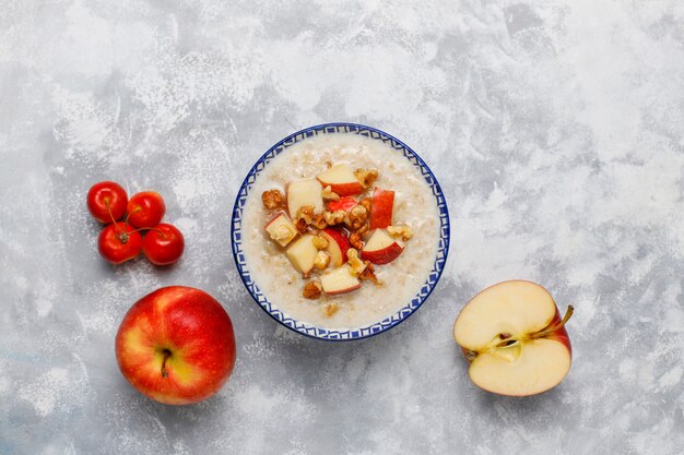 Oatmeal porridge in a bowl with honey and red apple slices,top view