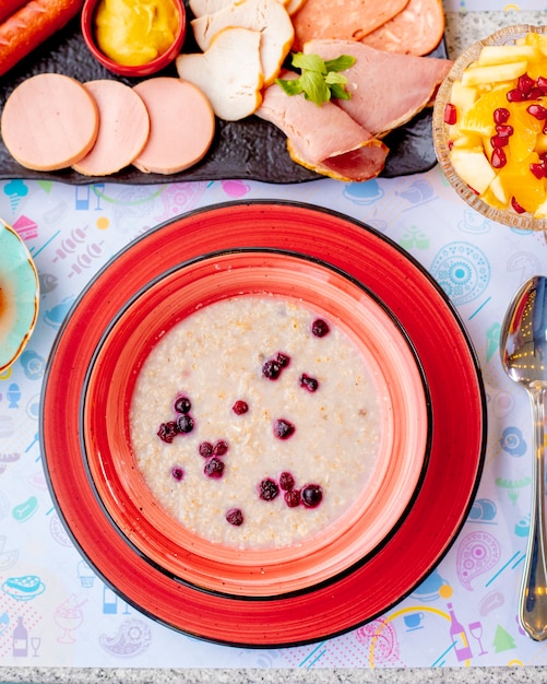 Free Photo oatmeal porridge with berries and meat plate on the table