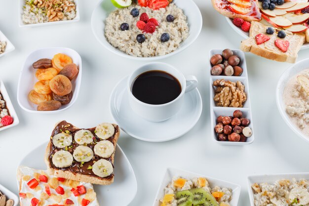 Oatmeal with fruits, nuts, coffee, fruit sandwich, dry apricots in plates