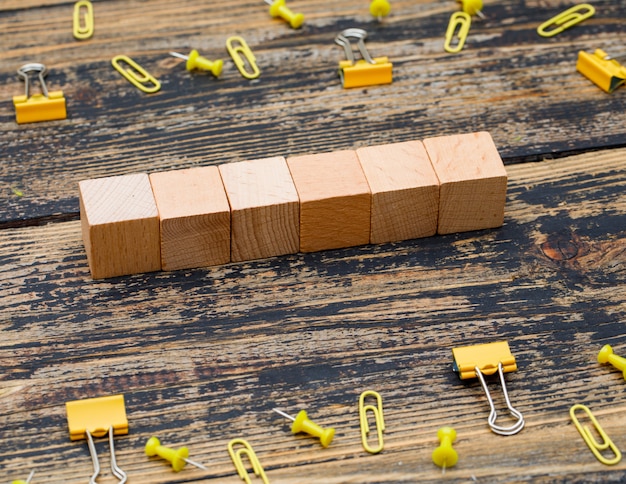 Free photo office concept with wooden cubes, paper clips, binder clips on wooden background high angle view.