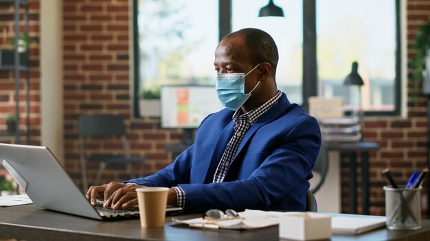 Office consultant planning financial statistics on laptop during coronavirus pandemic. Executive assistant using network information on online website application to create business strategy.