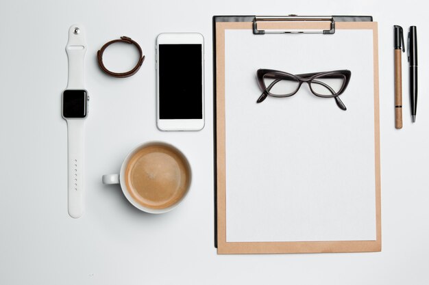 Office desk table with cup, supplies, phone on white