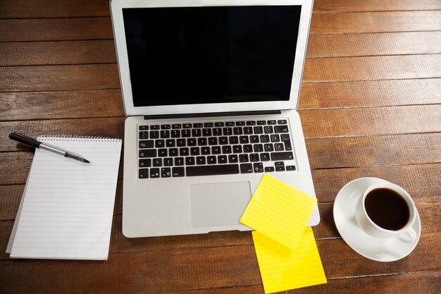 Office desk with laptop, notepad and cup of coffee