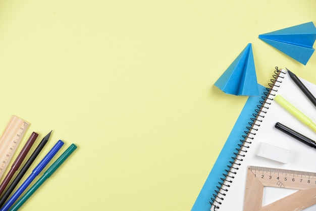 Free photo office stationaries and folded paper on yellow background