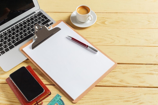 Office table background with coffee cup, pencils and computer keyboard. Business workplace or workspace concept.