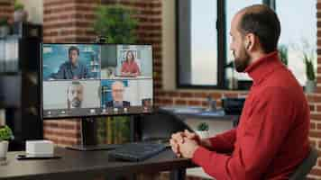 Free photo office worker attending videocall meeting with business people, talking about financial growth. male employee using remote videoconference chat to discuss on wireless communication. tripod shot.