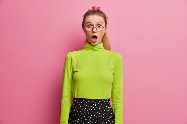 Free photo oh my god! excited emotional european teenage girl keeps mouth widely opened, realizes big problem, got in terrible situation, stares, wears green long sleeved turtleneck