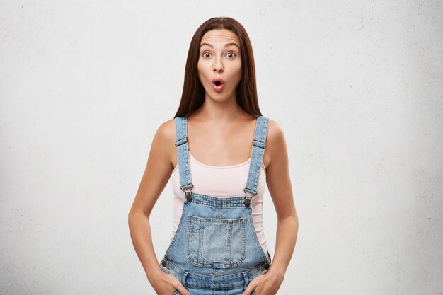 Oh my God. portrait of funny shocked young European woman with dark straight hair raising eyebrows and opening mouth in full disbelief