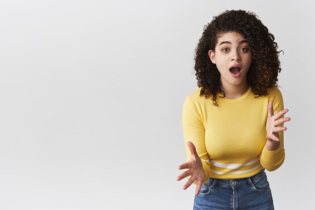 Oh my god spill tea Amused thrilled outgoing young nervous girl retelling awesome rumour gesturing excited talking warn friend be careful standing intense white background have conversation