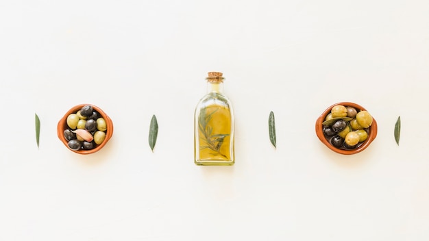 Free photo oil bottle with bowls with olives