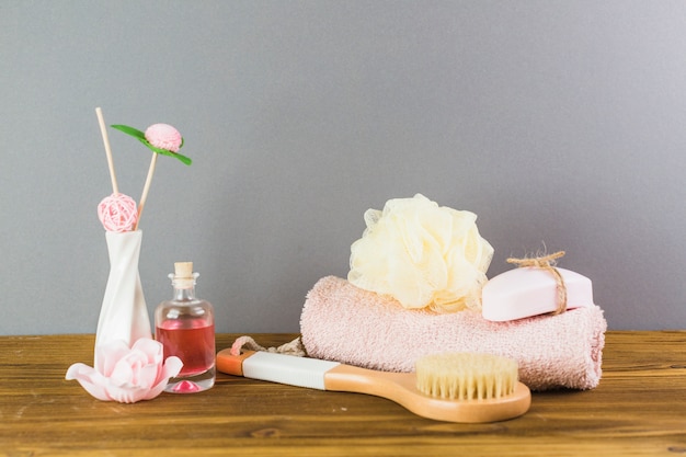 Free photo oil; brush; towel; loofah and soap on wooden tabletop