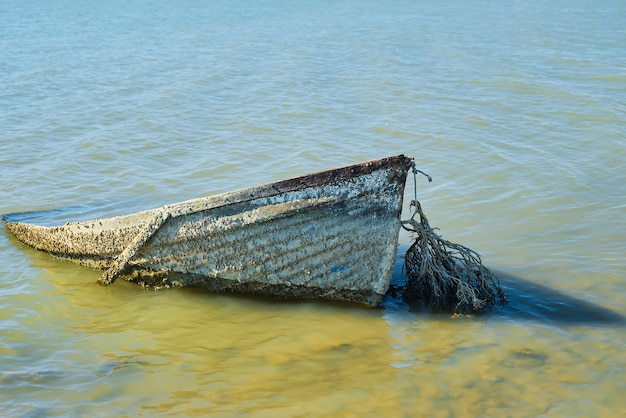 Free photo old abandoned boat sunken near the shore sunken or abandoned boat near the sea water pollution environmental problems and garbage pollution