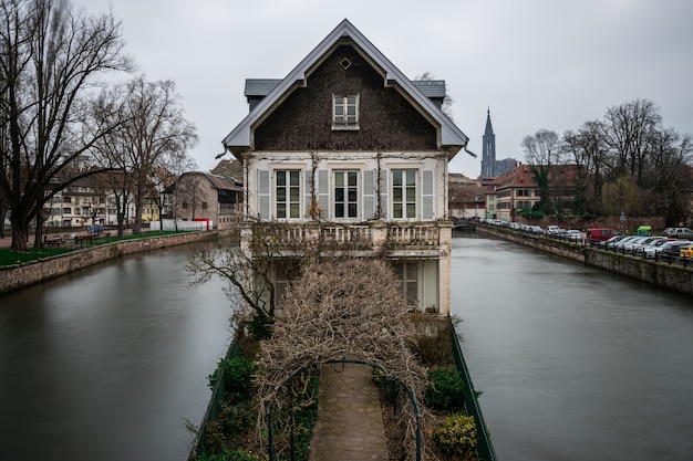 Free Photo old building surrounded by water and greenery under a cloudy sky in strasbourg in france