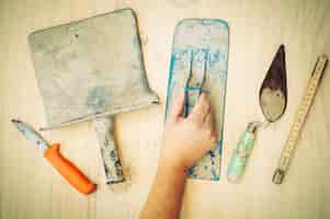 Free photo old construction hand tool with worker hand over white wooden background