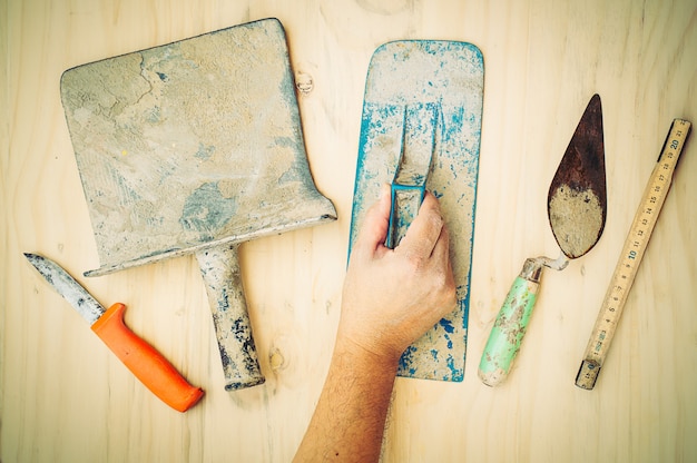 Free Photo old construction hand tool with worker hand over white wooden background